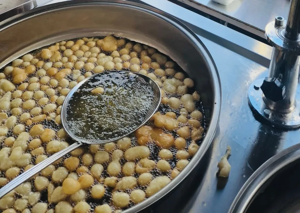 Lokma tavada altın rengini alıyor, kevgirle alınmaya hazır